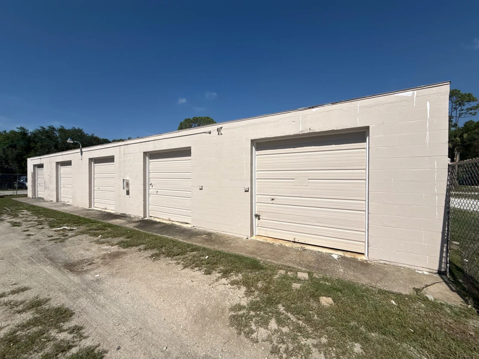 Commercial Painting in Florida Ridge, Florida. Single-storey commercial block building painted white with a row of roll-up garage doors, under a clear blue sky.