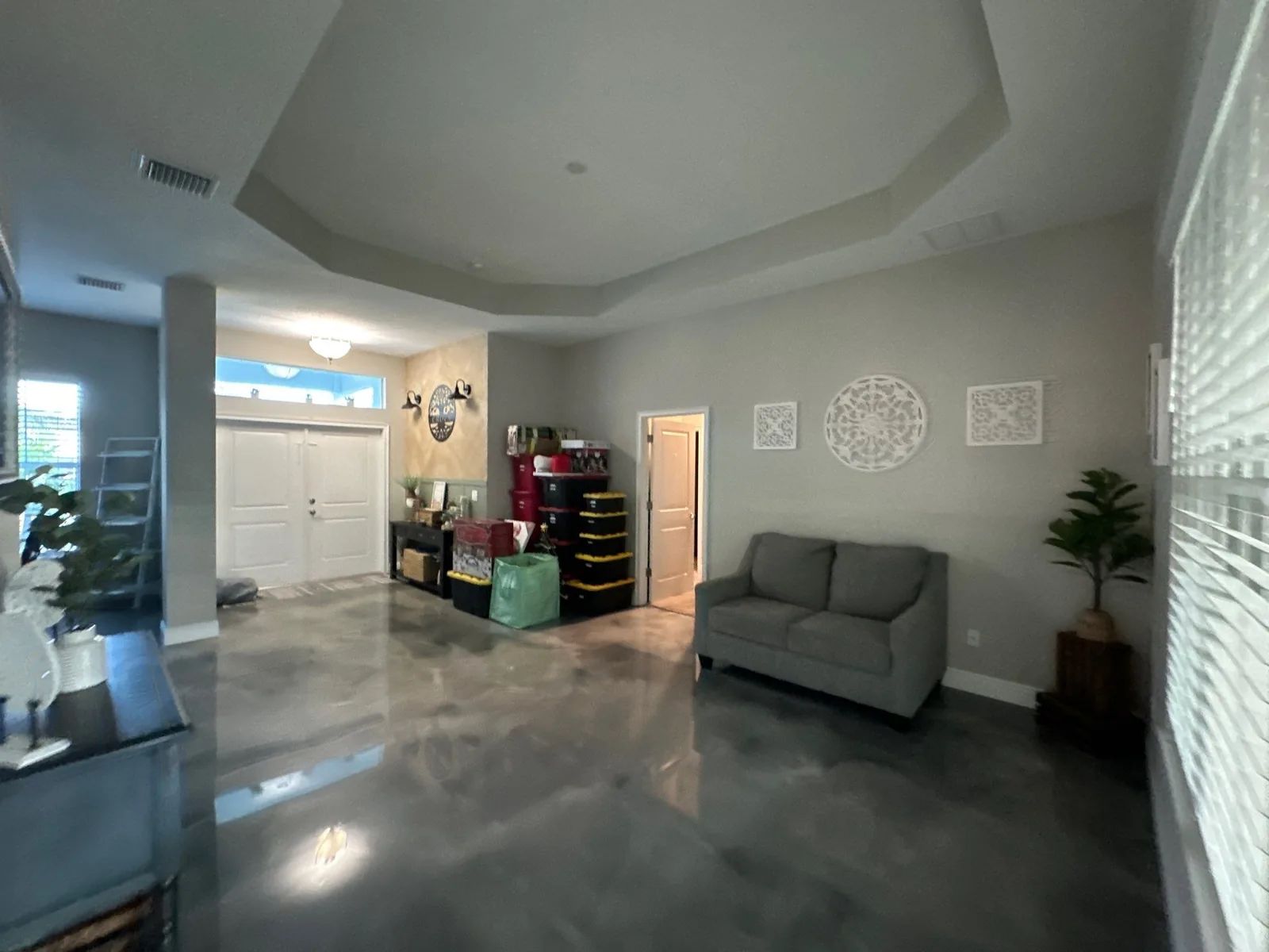 Interior Painting in Indian River Estates, Florida. Open living room with grey painted walls and stepped tray ceiling, polished concrete floor.