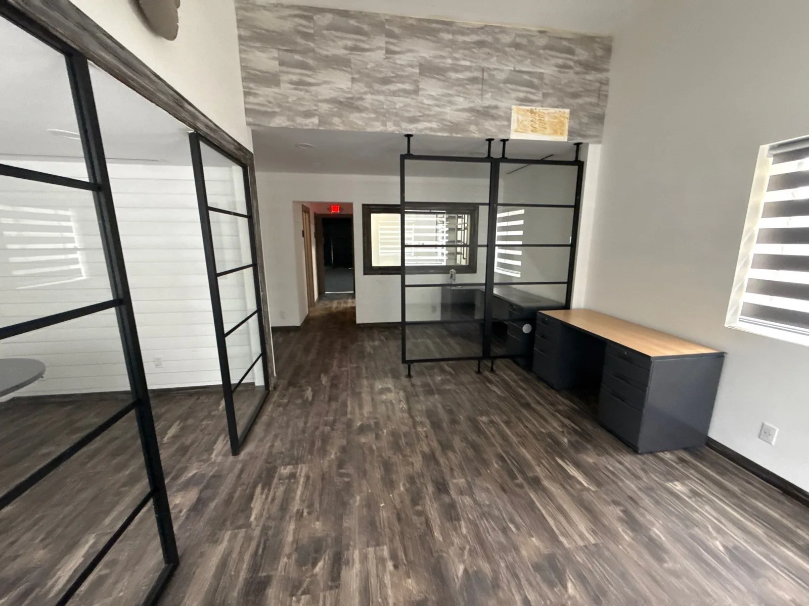 Commercial Painting in Jupiter, Florida. Empty commercial office interior with white horizontal-plank accent walls, black-framed glass partitions and dark wood-look flooring.