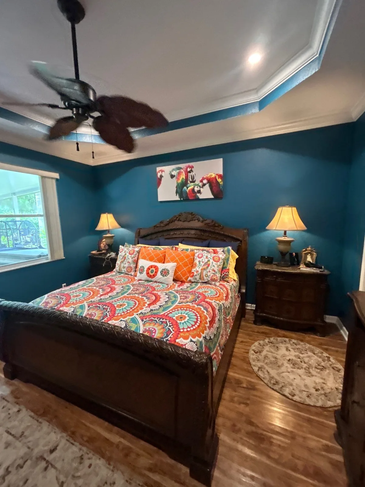 Interior Painting in Lakewood Park, Florida. Bedroom with teal walls and a white tray ceiling with crown moulding, dark wood bed, matching nightstands and lamps.