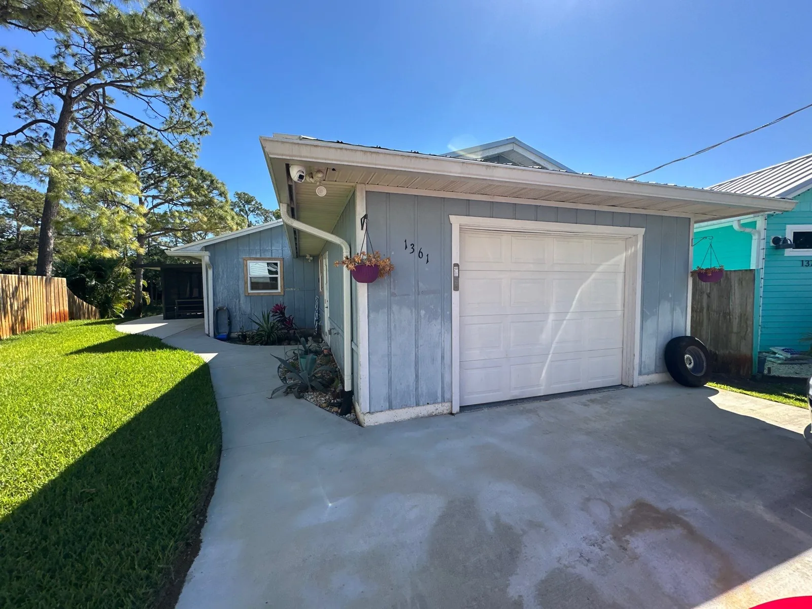 Exterior Painting in Palm City, Florida. Small single-storey house with pale blue-grey board-and-batten siding, white garage door and concrete driveway.