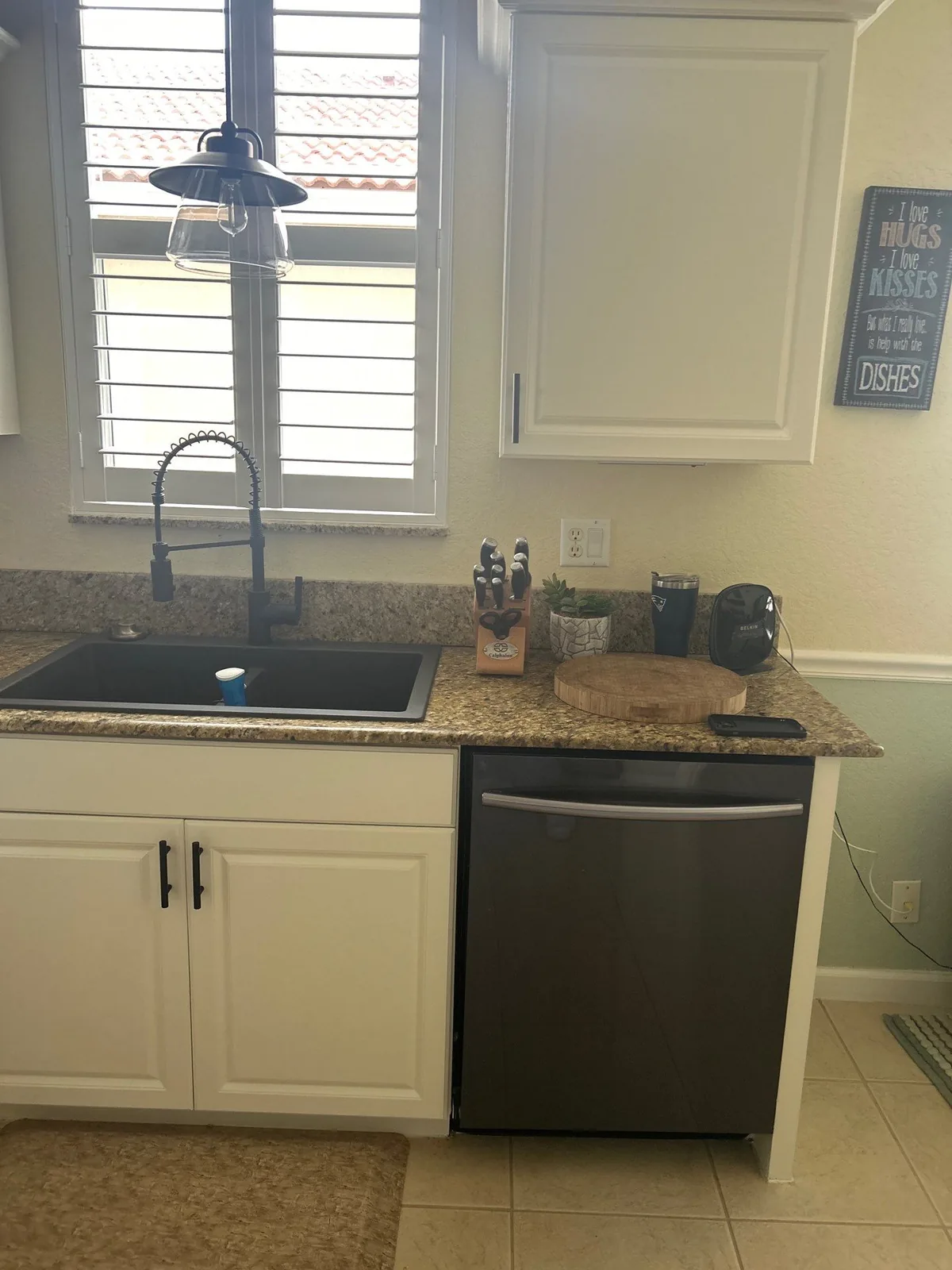 Cabinet Refinishing in Port Saint Lucie, Florida. Kitchen corner with white-painted cabinets, granite counter, undermount sink and stainless dishwasher.