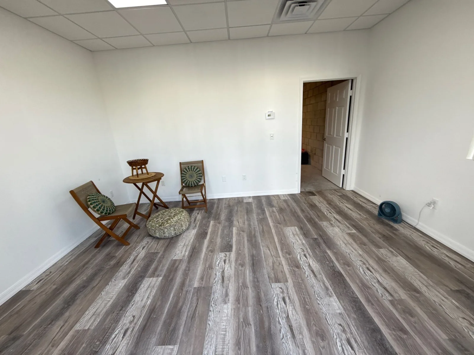 Commercial Painting in Port Saint Lucie, Florida. Empty commercial room with white walls, drop ceiling and grey wood-look plank flooring.