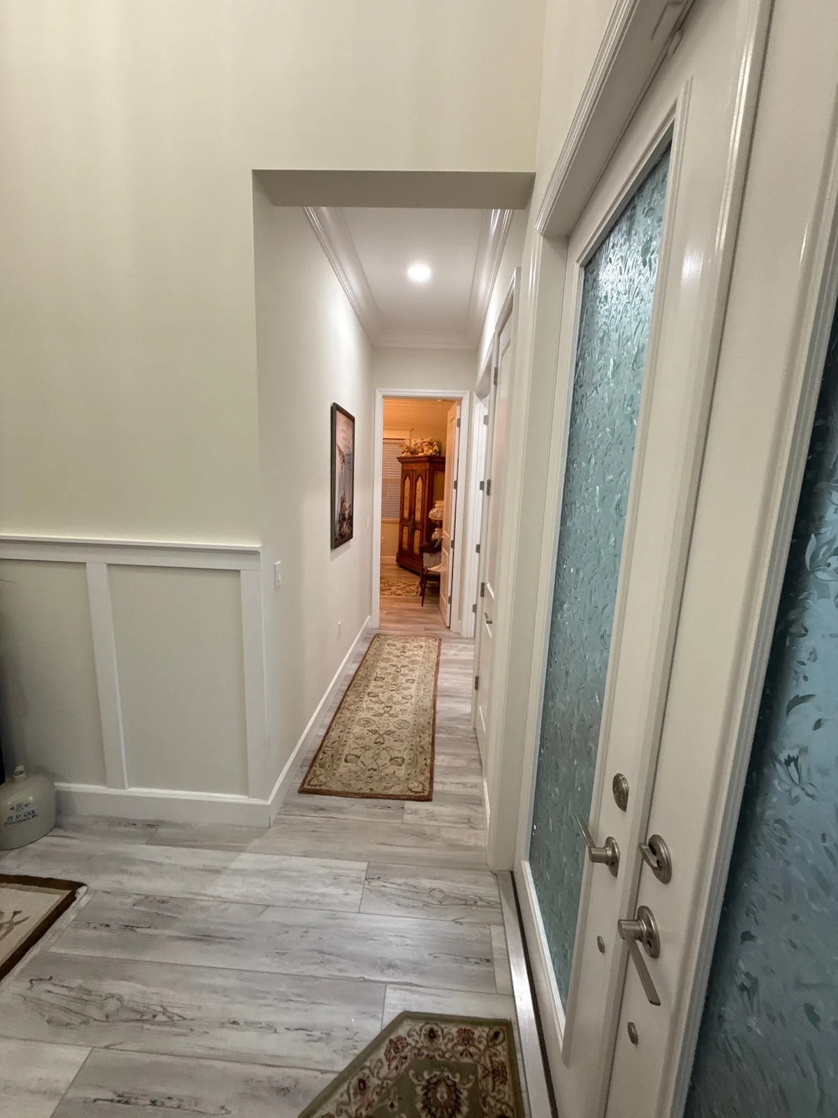 Interior Painting in Port Saint Lucie, Florida. Interior hallway with white painted walls, board-and-batten wainscoting, crown moulding and a runner rug.