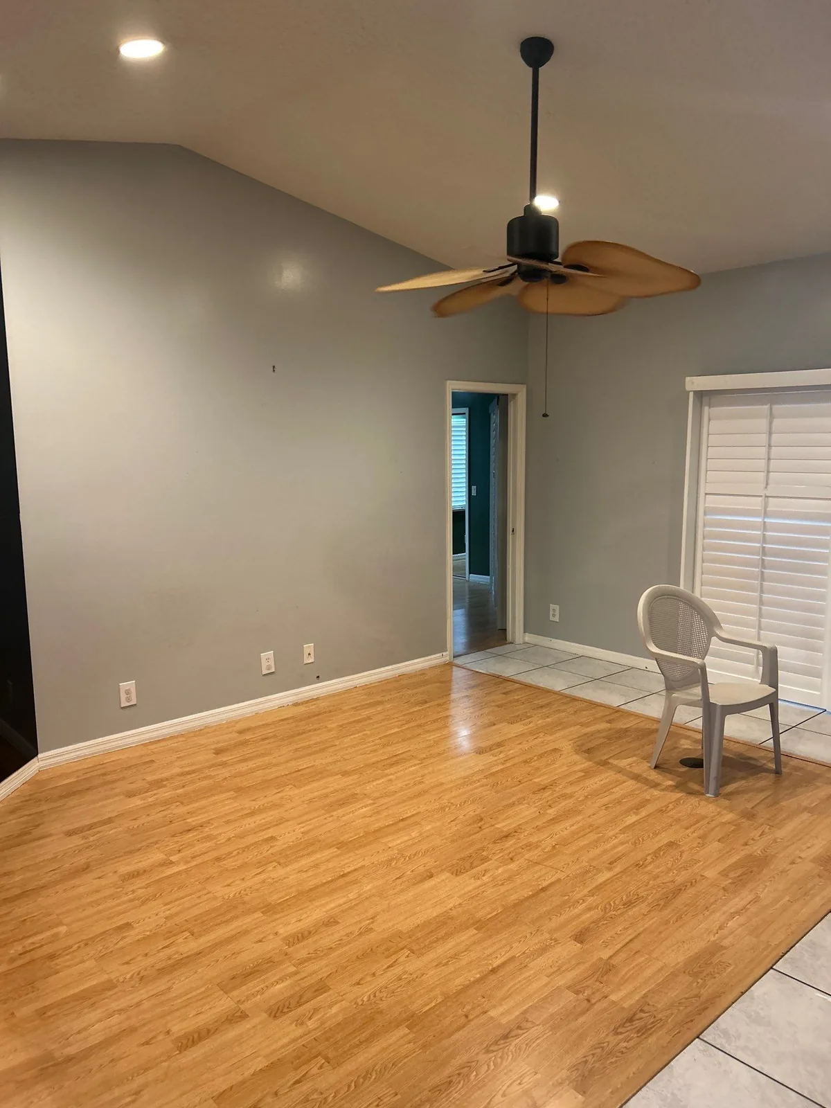 Interior Painting in Port Saint Lucie, Florida. Empty room with grey painted walls, white baseboards, a vaulted ceiling and wood-look flooring.