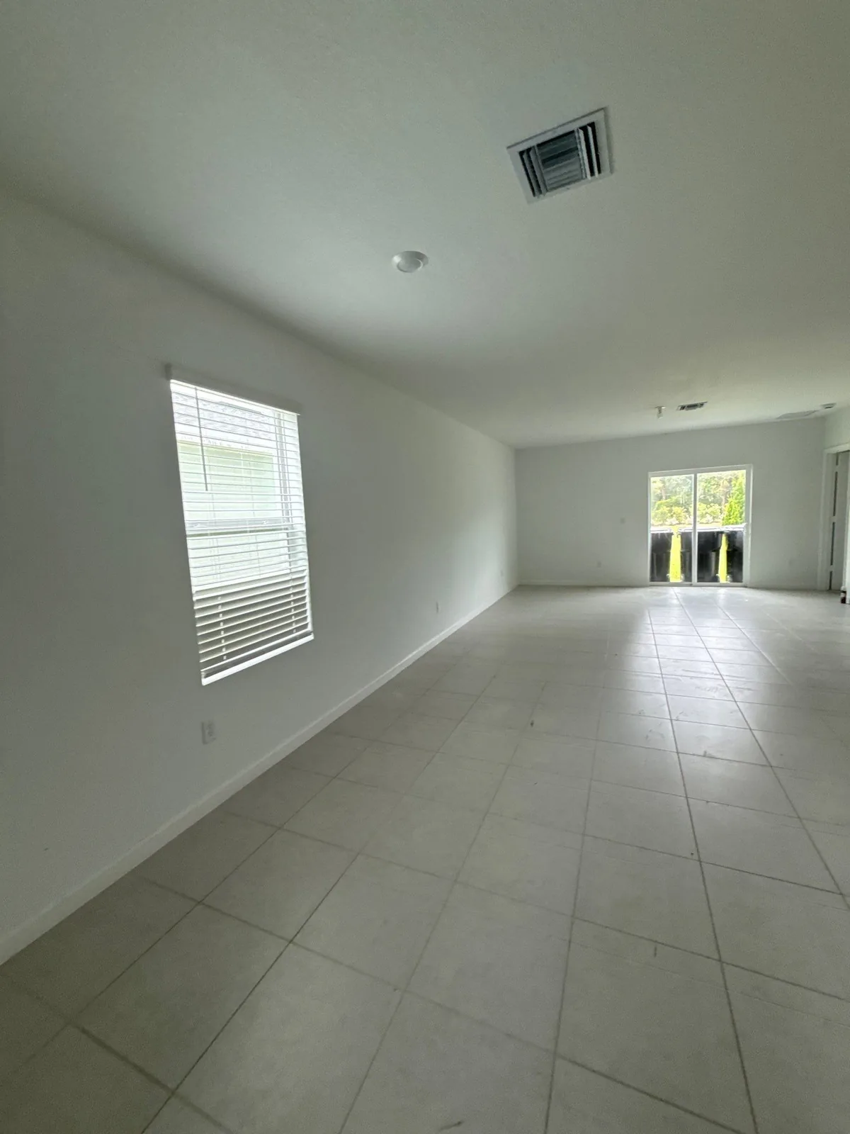 Interior Painting in Port Saint Lucie, Florida. Empty room with freshly painted white walls, a blinded window and large-format tile floor.