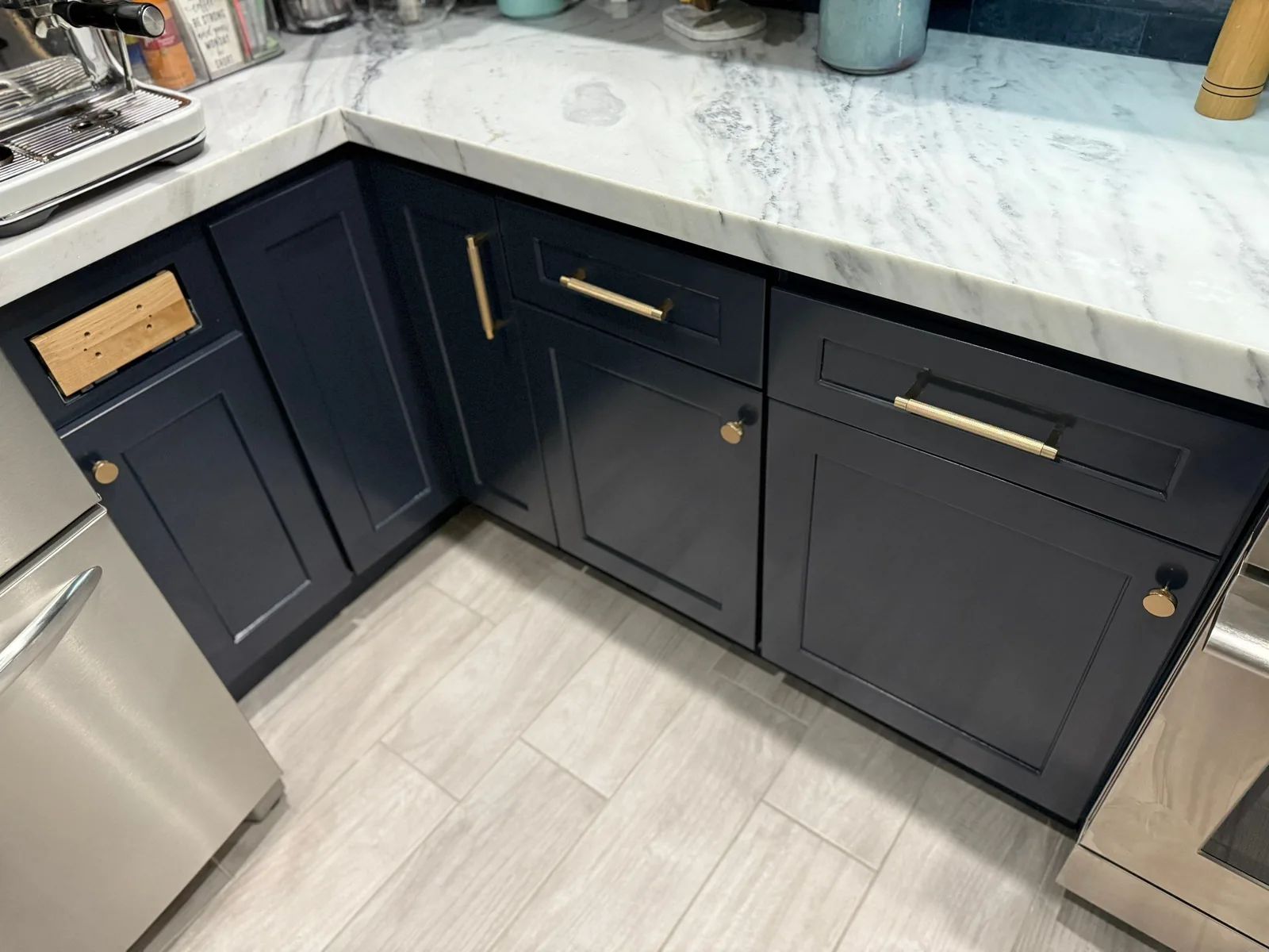 Cabinet Refinishing in Stuart, Florida. Navy blue shaker base cabinets with brass hardware, marble-look counter and stainless dishwasher.