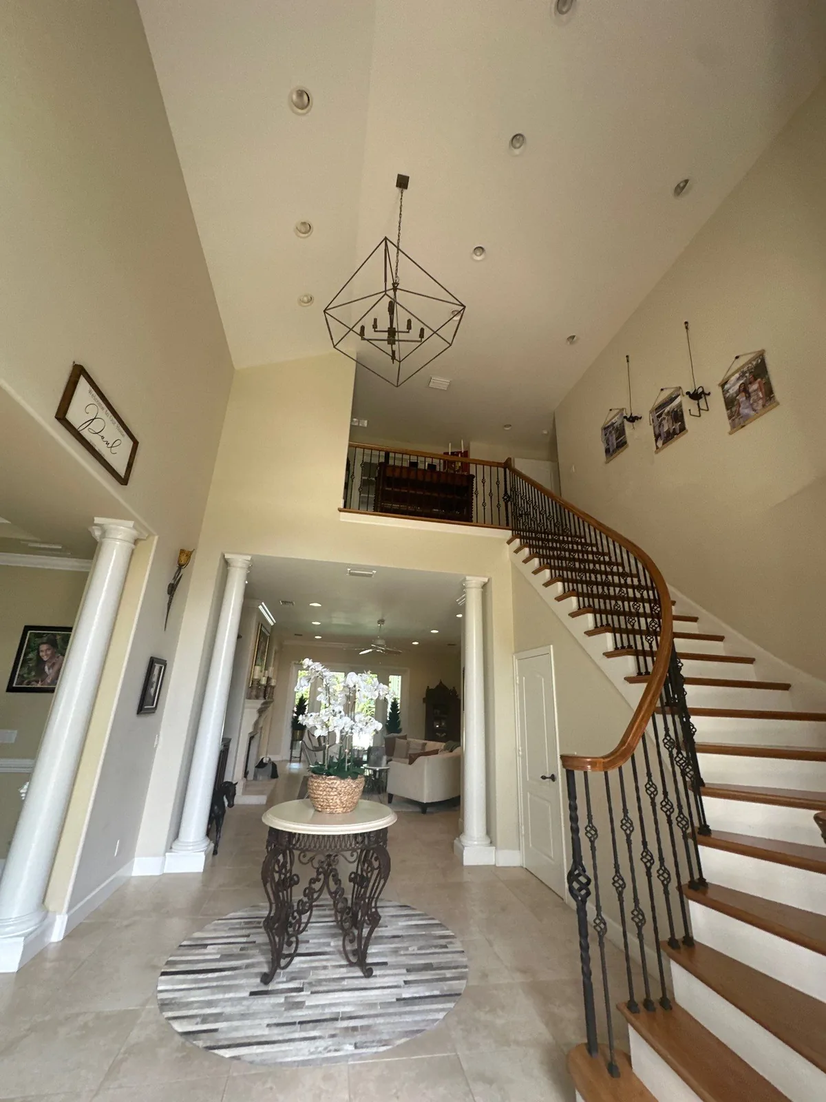 Interior Painting in Vero Beach, Florida. Two-storey entry foyer with vaulted painted ceiling, curved staircase with iron balusters, and painted columns and archway.